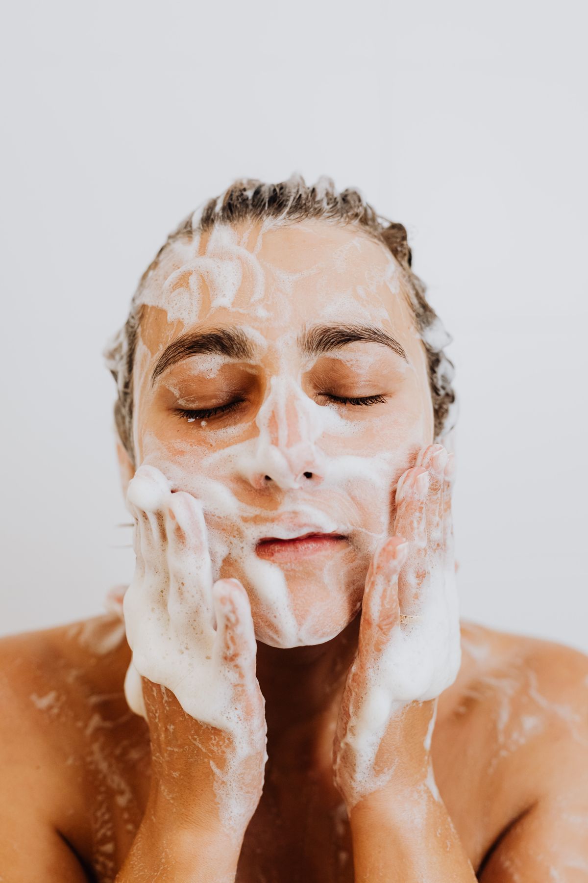 Gentle cleansing – woman washing her face with a delicate foam
