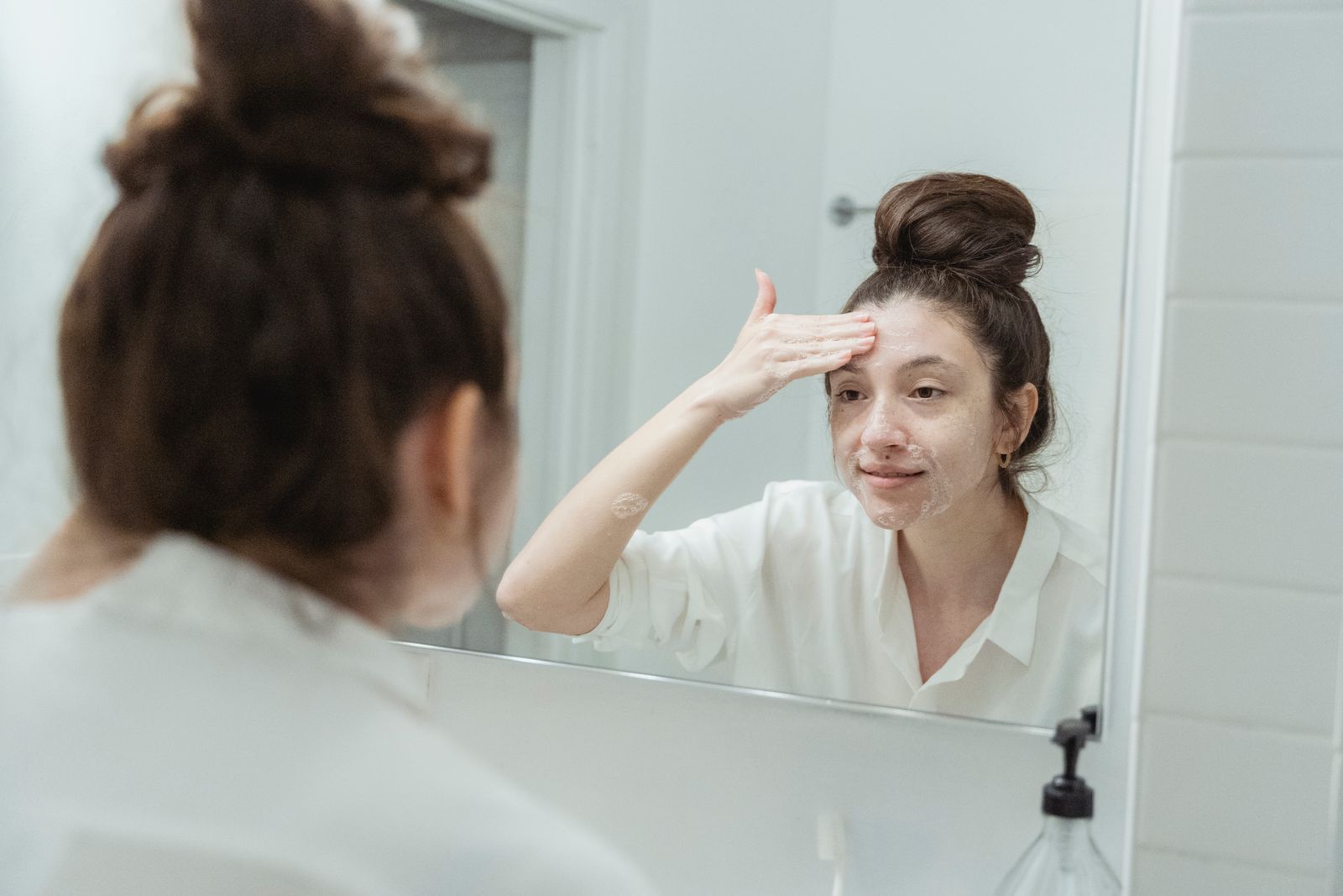 Woman applying cream in a minimalist bathroom – skincare in the spirit of Quiet Beauty